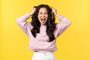 黄色の背景の前で頭を抱える女性